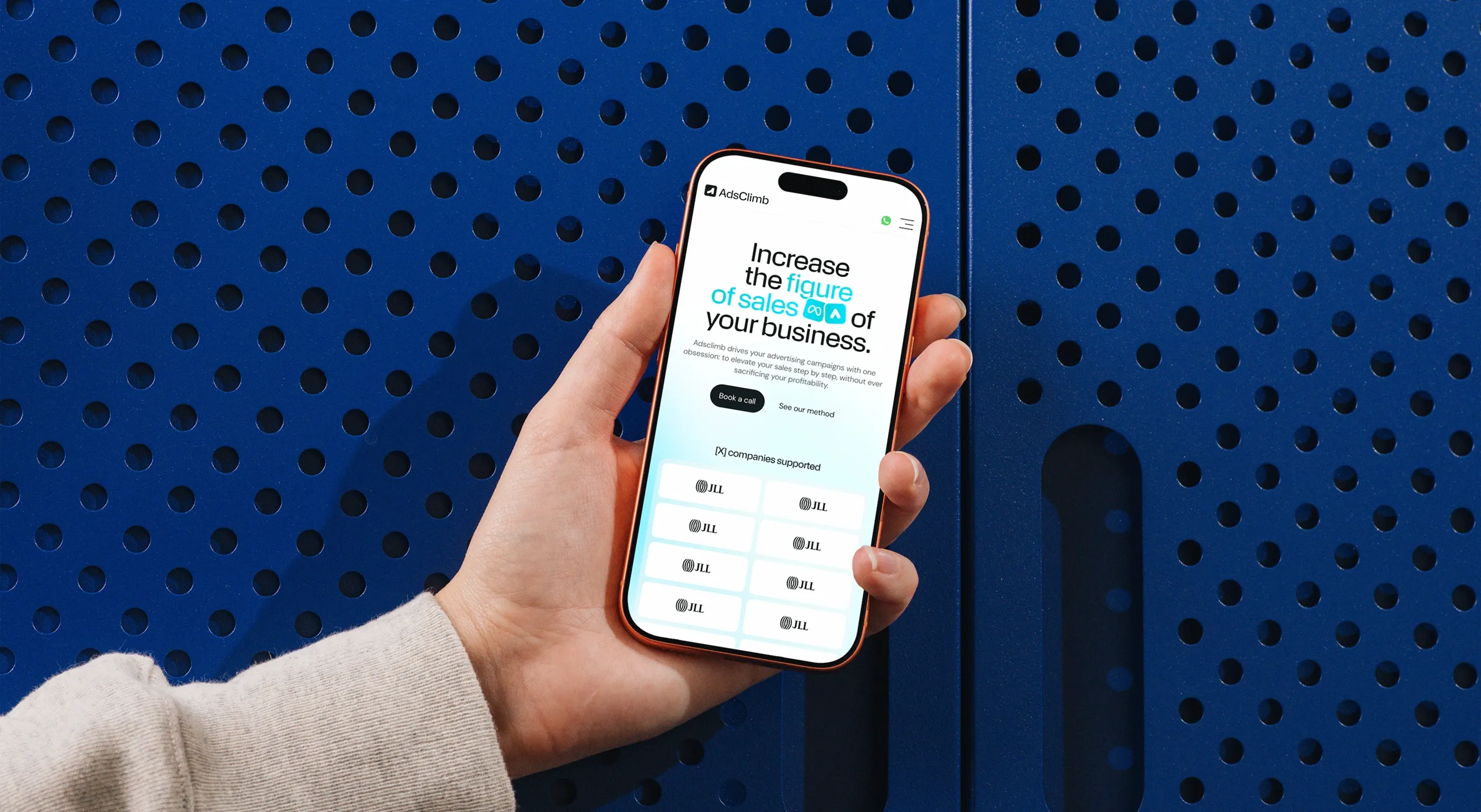 AdsClimb website on a phone held in hand